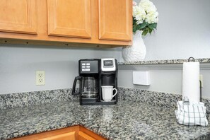 A kitchen with granite countertops, a coffee maker, a mug, and wooden cabinets. - Mountain View Condo 1306 (Pigeon Forge)
