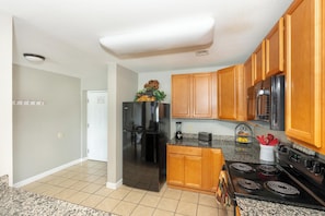A kitchen with wooden cabinets, a black refrigerator, a stove, and a microwave. - Mountain View Condo 1306 (Pigeon Forge)