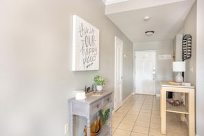 A hallway with a sign reading 'this is our happy place,' a potted plant, a console table with a lamp, and a door labeled 'RELAX.' - Mountain View Condo 1306 (Pigeon Forge)