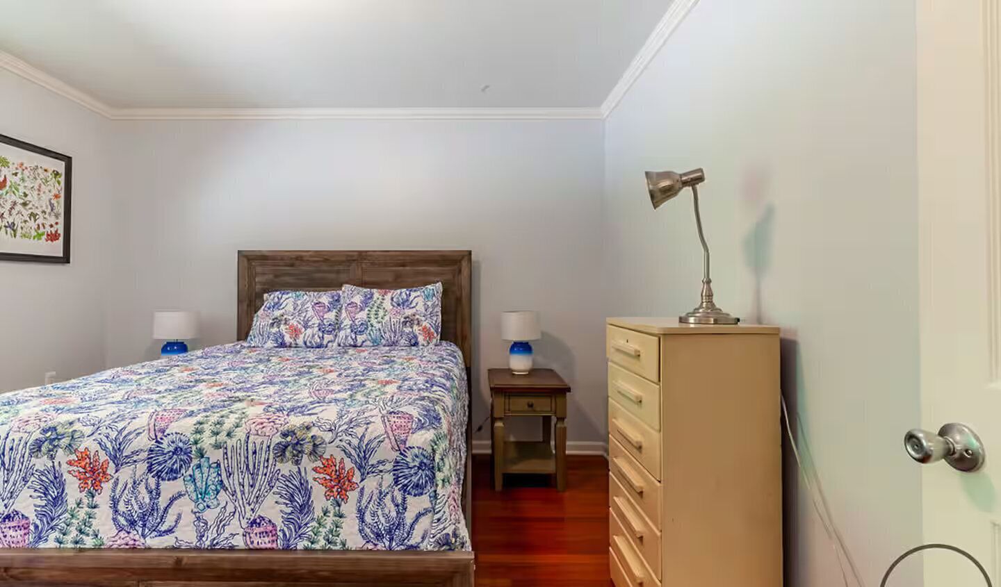 Un dormitorio con cama, mesitas de noche, cómoda y lámpara.