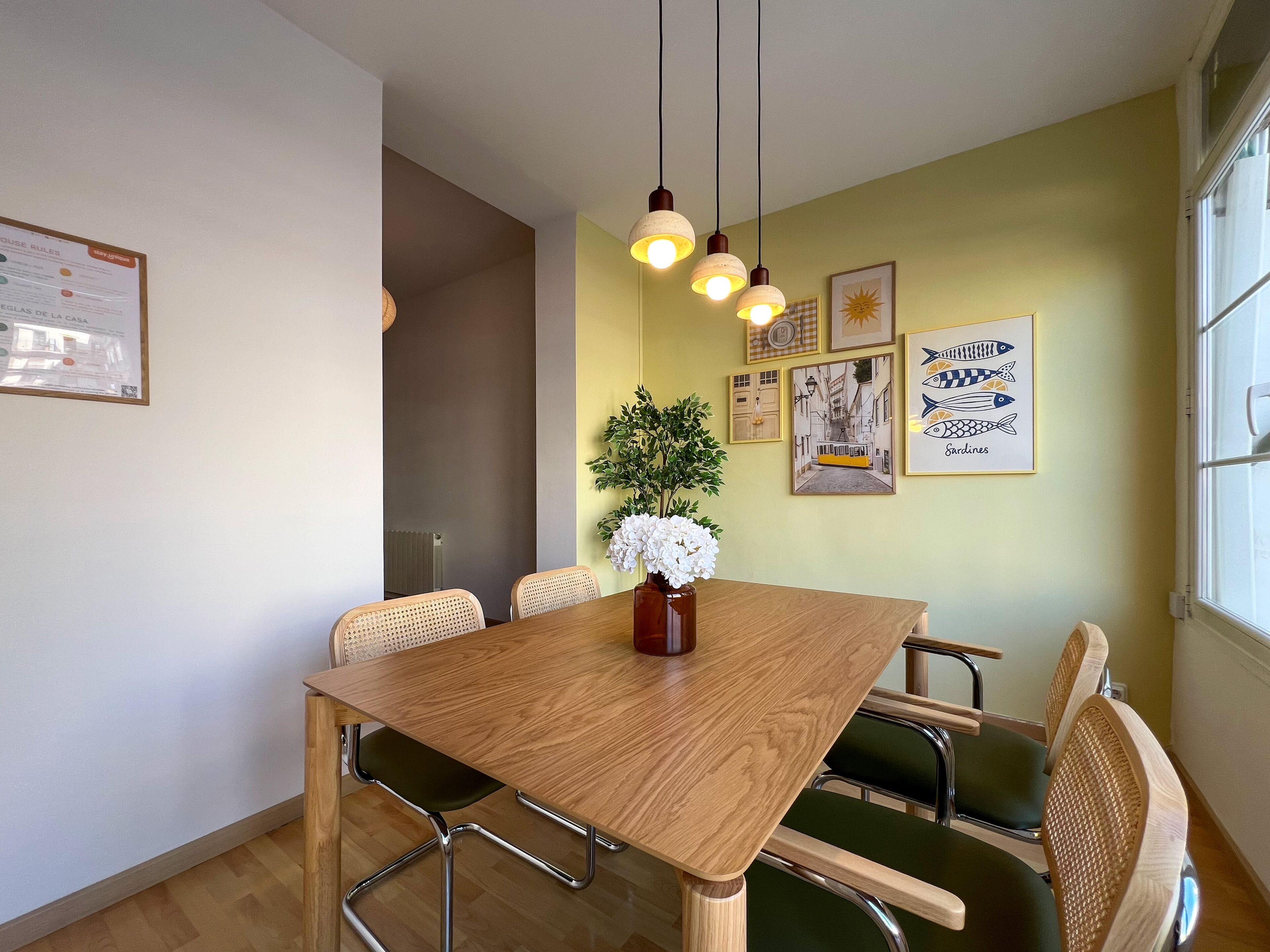 Een eetgedeelte met een houten tafel, stoelen en hangende lampen.