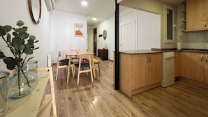 Een moderne keuken met houten kastjes, een inbouwvaatwasser en een eethoek met een tafel en stoelen.