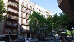 A street view with a row of multi-story buildings, parked cars, and a bus stop. - Stay U-nique Apartments Villarroel (Barcelona)