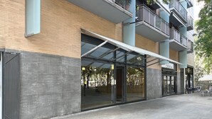 A modern building with a glass entrance, a covered outdoor seating area, and a brick facade.
