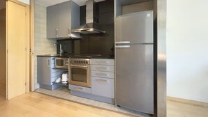 A compact kitchen with a built-in oven, microwave, and stainless steel refrigerator.