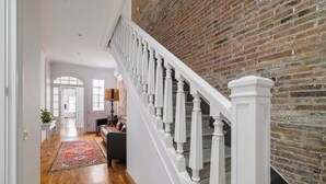 A staircase with white balusters leading to a brick wall. A hallway with wooden flooring and a red patterned rug is visible. - Stay U-nique Apartment Creu Coberta II (Barcelona)