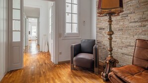 A spacious room with a wooden parquet floor, a brick wall, and a large window. - Stay U-nique Apartment Creu Coberta II (Barcelona)