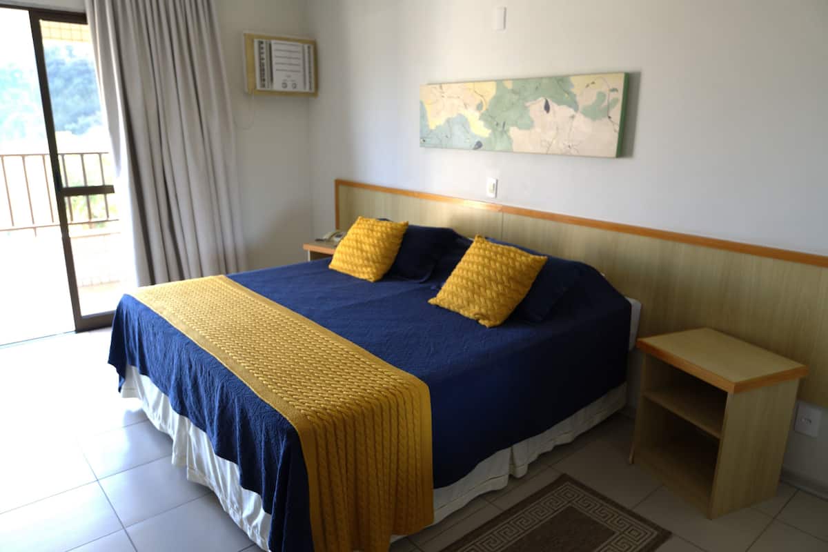 A neatly made bed with a blue and yellow bedspread, two matching pillows, and a wooden nightstand with a lamp.
