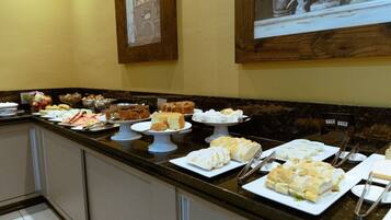A buffet with various food items including cakes, pastries, and sandwiches.