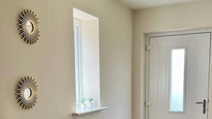 A hallway with a white door, a small window, and a potted plant on a console table. - 4BR Lymington Home near New Forest & Coast (Hampshire)