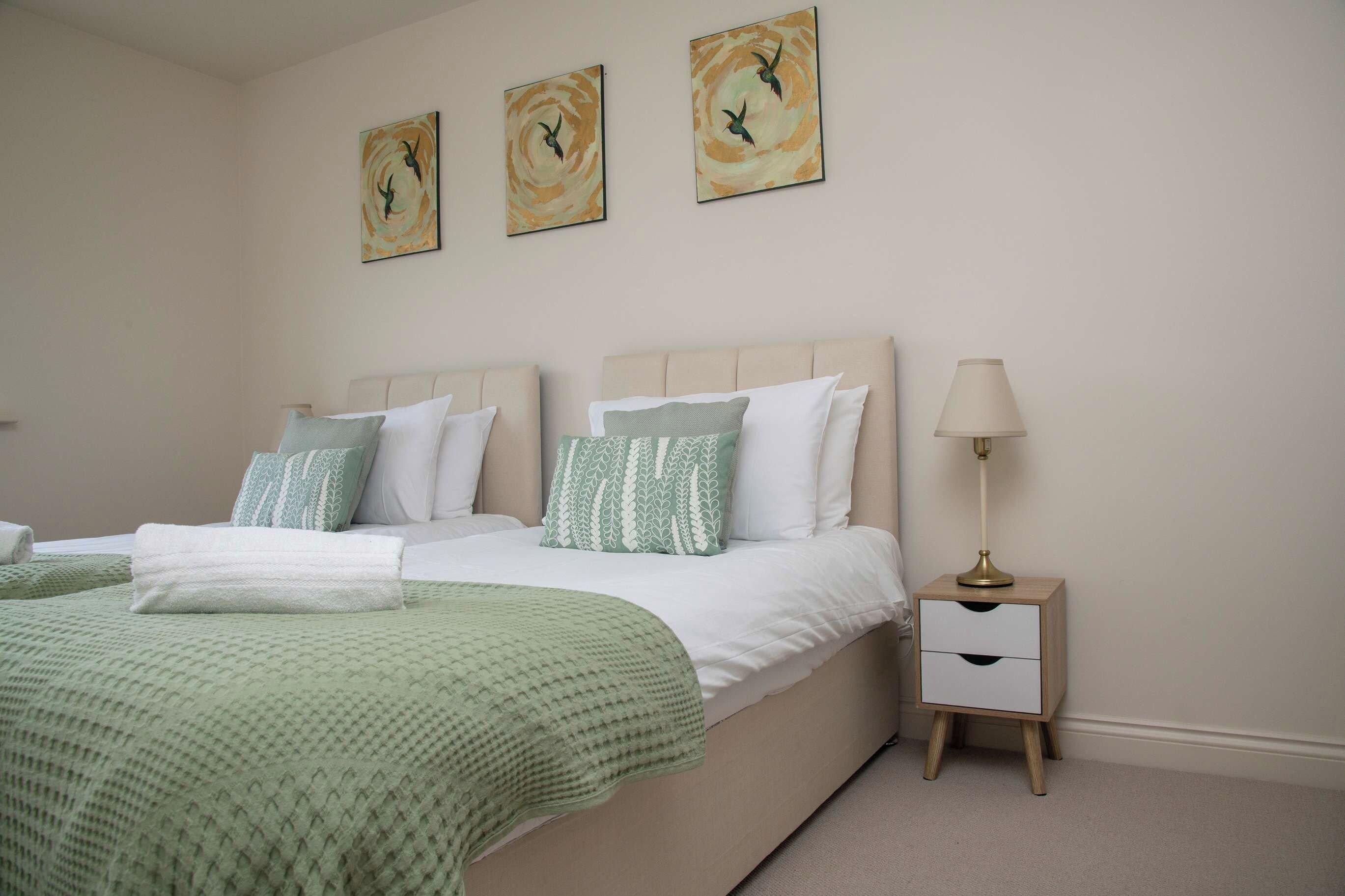 A bedroom with a bed, pillows, a bedside table, and a lamp.