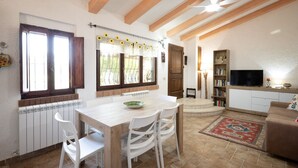 A spacious living area with a dining table, white chairs, a sofa, a TV, and a bookshelf. - La Casa dei Quadri - Gavorrano (Bivio di Ravi Gavorrano)