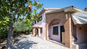 A two-story house with a stone-paved courtyard, a small archway entrance, and a covered porch. - La Casa dei Quadri - Gavorrano (Bivio di Ravi Gavorrano)