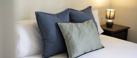 A bed with two pillows and a nightstand with a lamp.
