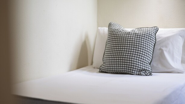 A bed with a checkered pillow and a plain white pillow against a plain wall. - Stay U-nique Apartments Sagrada Familia (Barcelona)