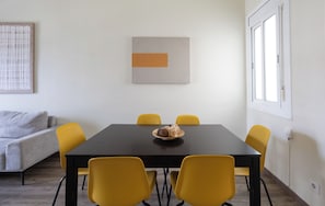 A dining area with a black table, four yellow chairs, and a bowl of food on the table. - Stay U-nique Apartments Sagrada Familia (Barcelona)