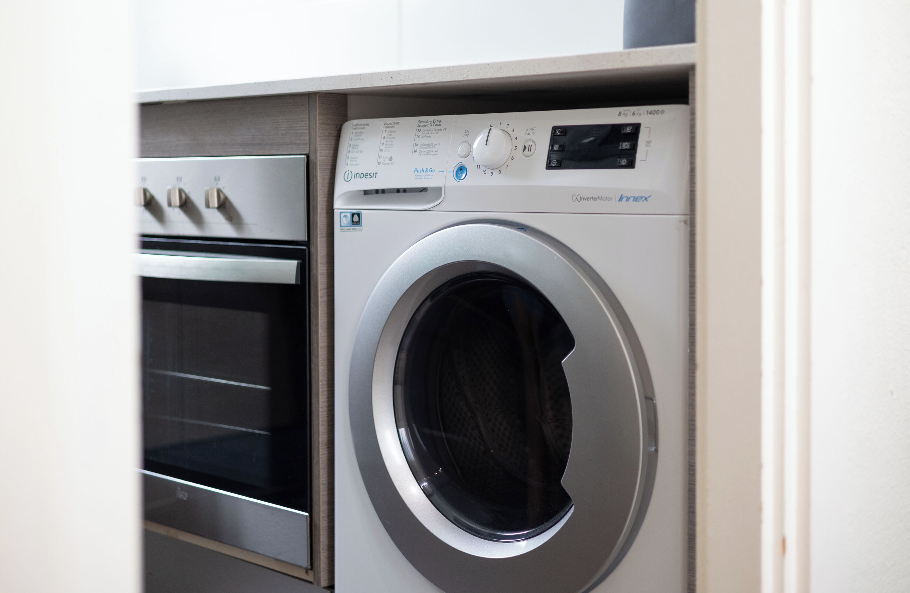 Una unidad compacta de lavadora y secadora con panel de control y horno de acero inoxidable.