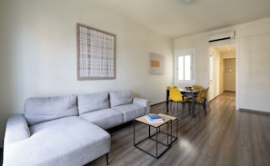 A modern living room with a grey sectional sofa, a small coffee table, and a dining area with yellow chairs. - Stay U-nique Apartments Sagrada Familia (Barcelona)