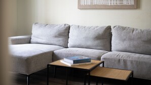 A grey sofa with a small wooden table and a book in front of it. - Stay U-nique Apartments Sagrada Familia (Barcelona)