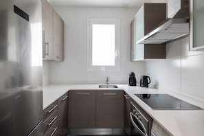 A modern kitchen with a built-in oven, a sink, and a window above the countertop. - Stay U-nique Apartments Sagrada Familia (Barcelona)