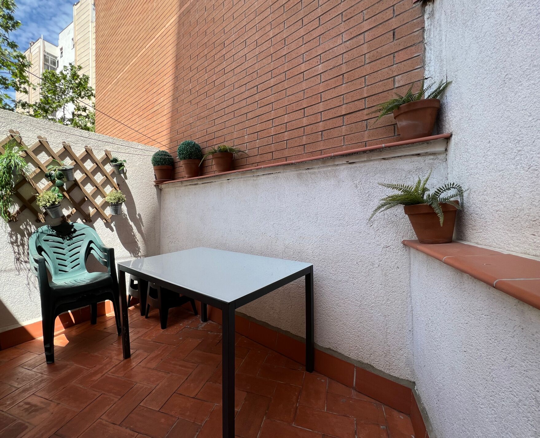 A patio with a table and chairs, potted plants, and a brick wall.