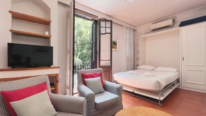 Een kamer met een bed, twee fauteuils, een televisie en een houten tafel.