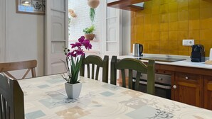 Een moderne keuken met een wit aanrecht, een gele spatwand en een eethoek met een tafel en stoelen.