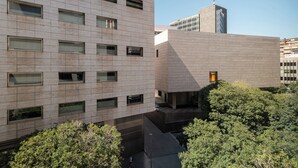 Un bâtiment moderne doté d’une façade à motifs géométriques de fenêtres et d’une cour intérieure plantée d’arbres.
