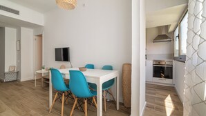Une cuisine moderne dotée d’un four encastré et d’un coin repas avec une table blanche et des chaises bleues.