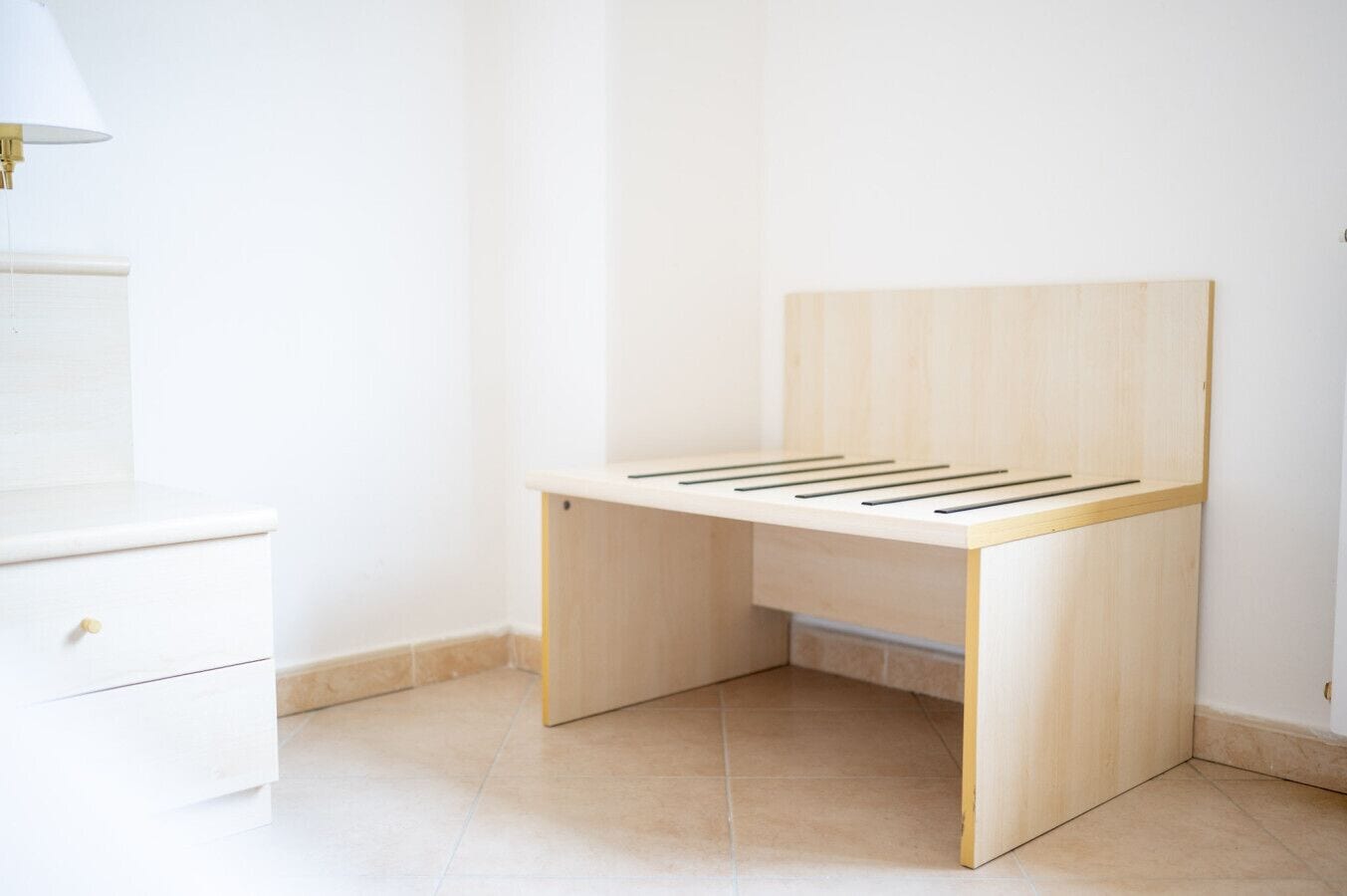 Habitació minimalista amb escriptori de fusta, un ambigú blanc i una làmpada.
