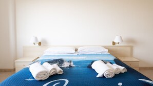 Une chambre d’hôtel avec un lit, deux lampes de chevet, une couvre-lit bleue et des serviettes pliées sur le lit.