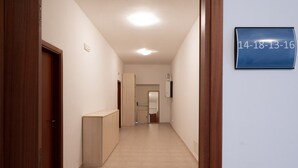 Un couloir avec une porte en bois sur la gauche, un comptoir d’accueil et un panneau indiquant des dates sur la droite.