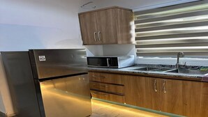 A modern kitchen with stainless steel appliances, wooden cabinets, and a built-in microwave.