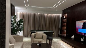 A modern living room with a sectional sofa, a pool table, and a flat-screen TV.