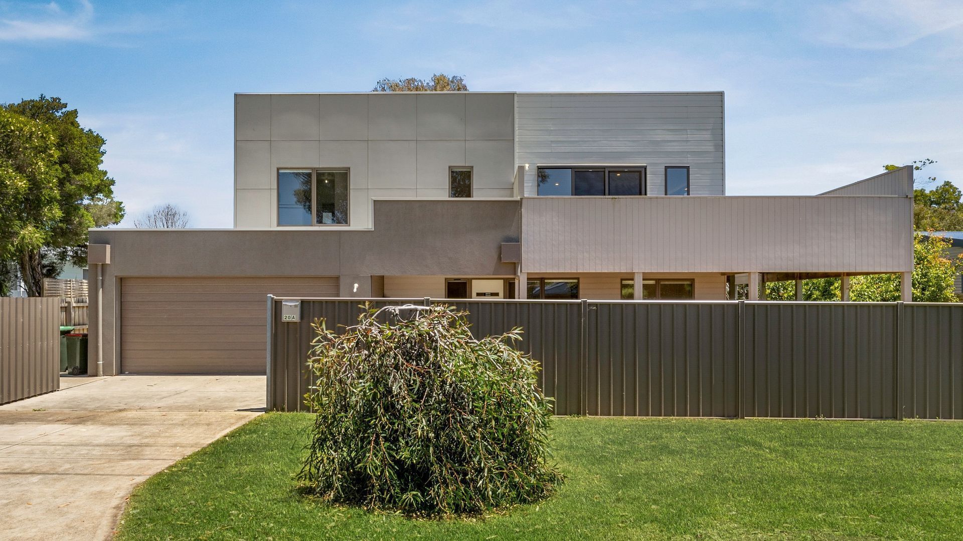 A modern two-story house with a flat roof, a garage, and a well-maintained lawn.