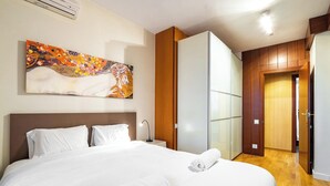 Une chambre d’hôtel avec un grand lit, une table de chevet, un tableau accroché au mur et une armoire en bois.