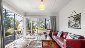 A spacious living room with a red leather sofa, a wooden coffee table, and a large glass door leading to an outdoor deck.