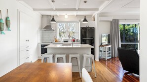 A modern kitchen with white cabinetry, a central island, and a dining area with a wooden table.