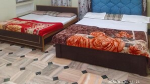 Habitación de hotel con dos camas, un ventilador de techo y un calentador en la pared.