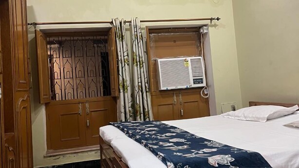 Un dormitorio con cama de madera, ventana con cortinas y una lámpara en el techo.