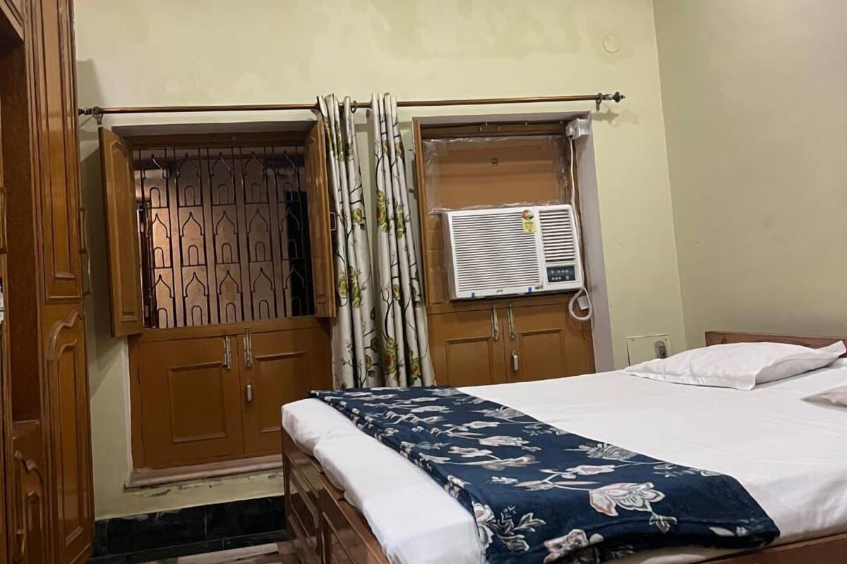 Un dormitorio con cama de madera, ventana con cortinas y una lámpara en el techo.
