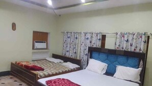 Habitación de hotel con dos camas, un televisor de pantalla plana en la pared y cortinas estampadas.