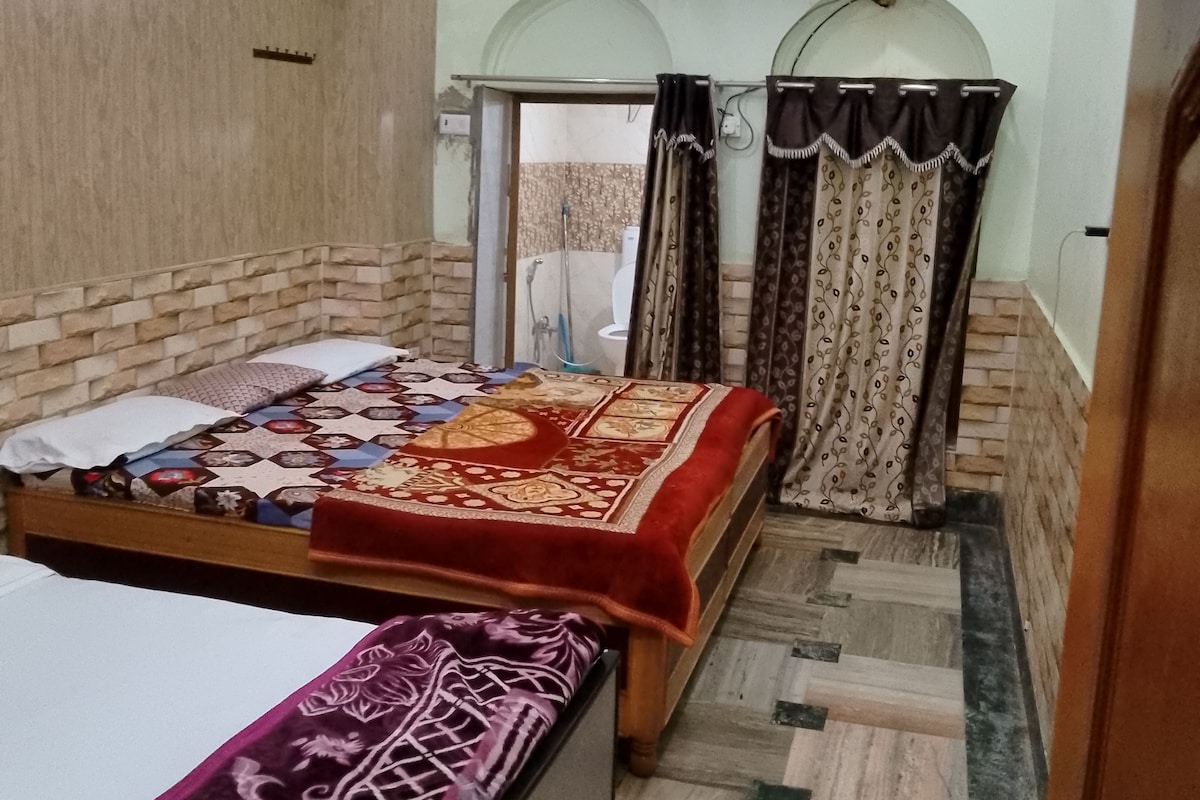 A bedroom with two beds, a shower area, and a patterned floor.