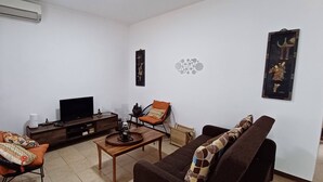 Un salon comprenant un téléviseur, un canapé, une table basse et des coussins décoratifs.