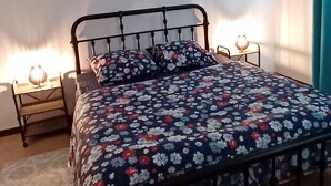 Une chambre à coucher comprenant un lit, une table de chevet, une lampe fixée au mur et un luminaire au plafond.