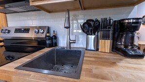 A modern kitchen with stainless steel appliances, a black sink, and wooden countertops. - National Parks - Cowboy Hot tub and UFO Sightings (Alton)