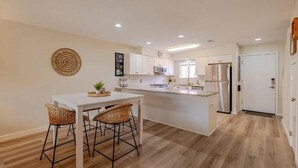 A modern kitchen with white cabinets, a central island, and bar stools. - Gulf Highlands 229- St. Katherine Blvd (Panama City Beach)