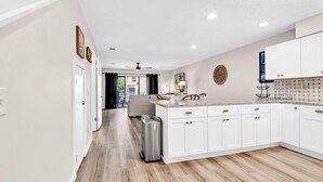 A modern kitchen with white cabinetry, a granite countertop, and a stainless steel trash can. - Gulf Highlands 229- St. Katherine Blvd (Panama City Beach)