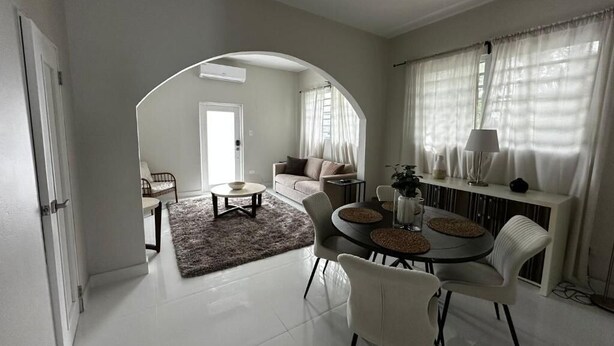 A modern living room with a dining area, featuring a sofa, coffee table, and a dining table with chairs.