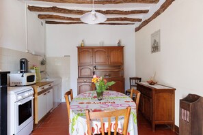 A kitchen with a dining table, wooden cabinets, a microwave, and a stove. - Holiday Home Gîte 35 for 4 Guests (Noyers-sur-Cher)